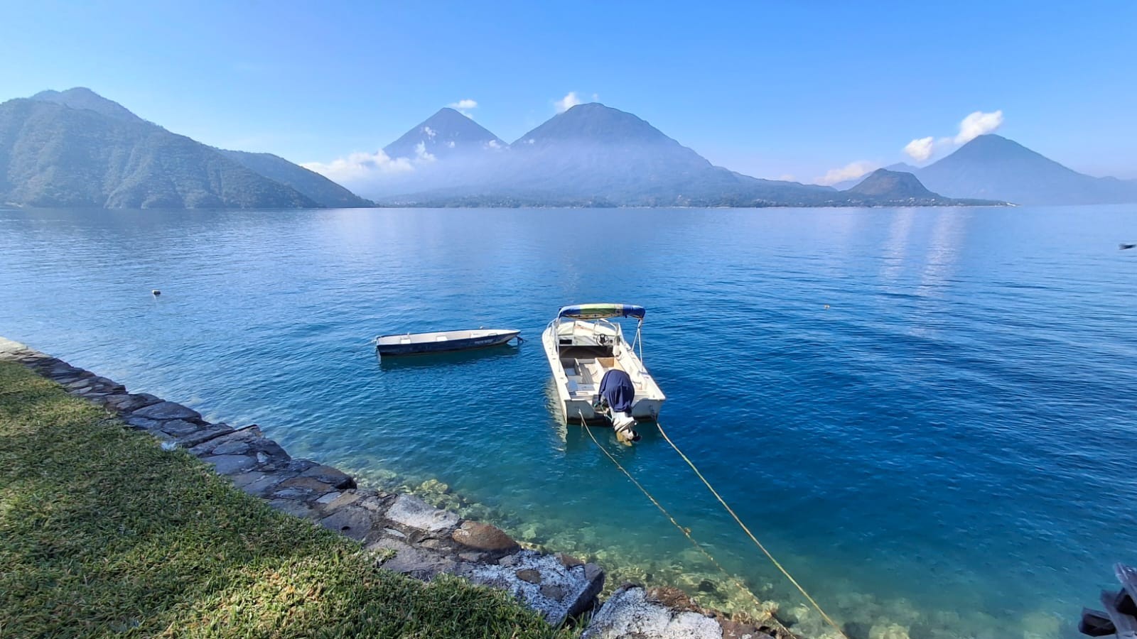 Three volcanoes mirrored in the still water of Lago Atitlán at dawn